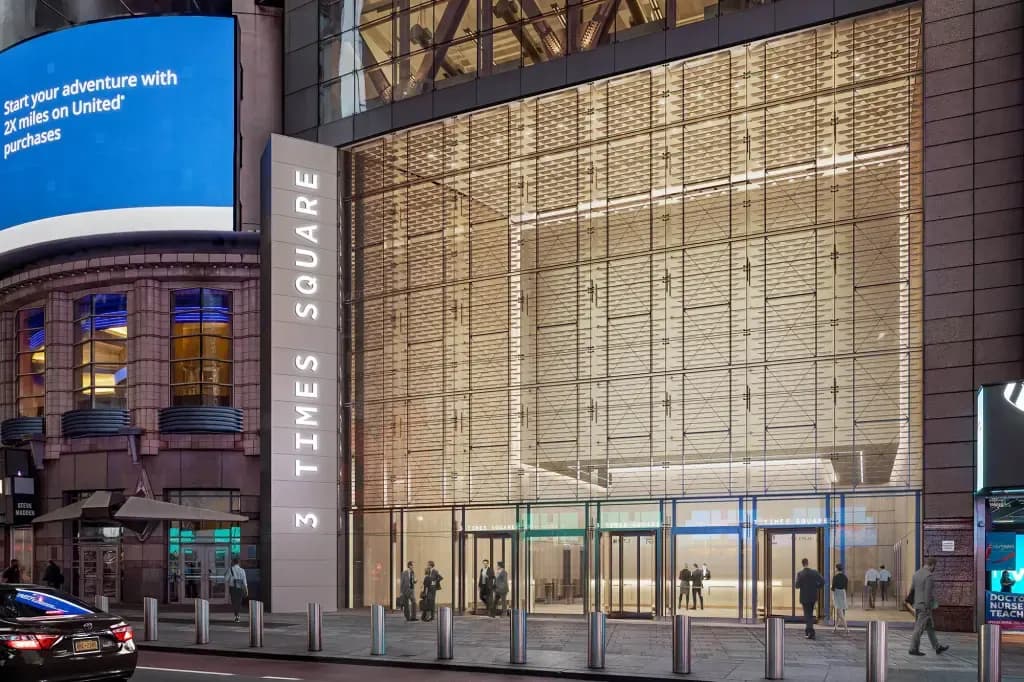 Street-level exterior of 3 Times Square in Manhattan at dusk with the building name on the facade