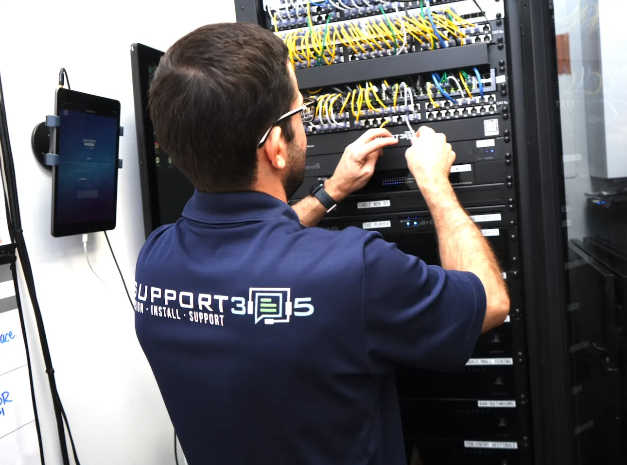 Technician terminating cabling in an AV and network rack