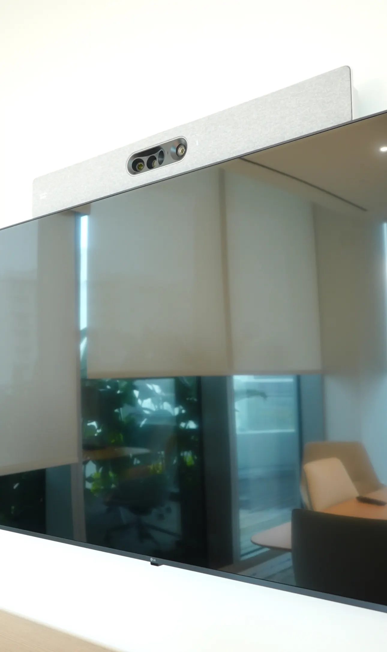 Wall-mounted commercial display with a video bar above it in a meeting room