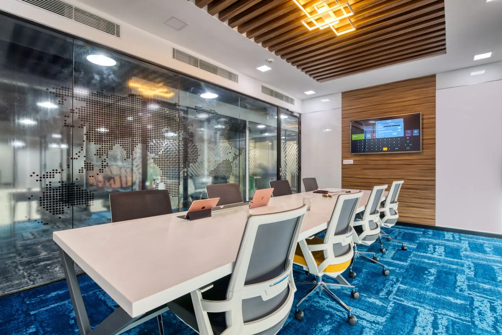 Modern boardroom with a long white table and a wall-mounted display at the far end