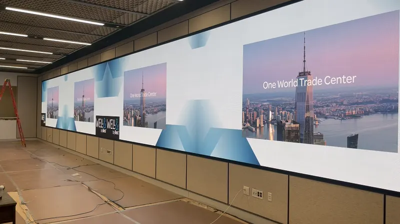 Wide LED video wall spanning a multipurpose room wall during installation, displaying One World Trade Center imagery